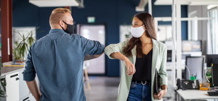 Two business colleagues greeting with elbow in office. Business people bump elbows in office for greeting during covid-19 pandemic. Pass sanitaire : les étapes essentielles de la mise en œuvre de la loi du 5 août 2021